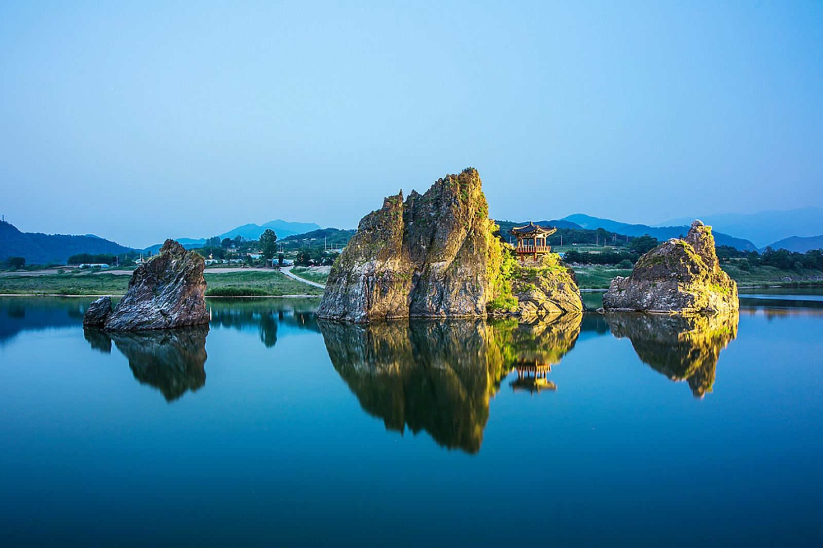 The three rocky peaks of Dodamsambong rising from the Namhan River in Danyang at blue hour, a pavilion on the central peak