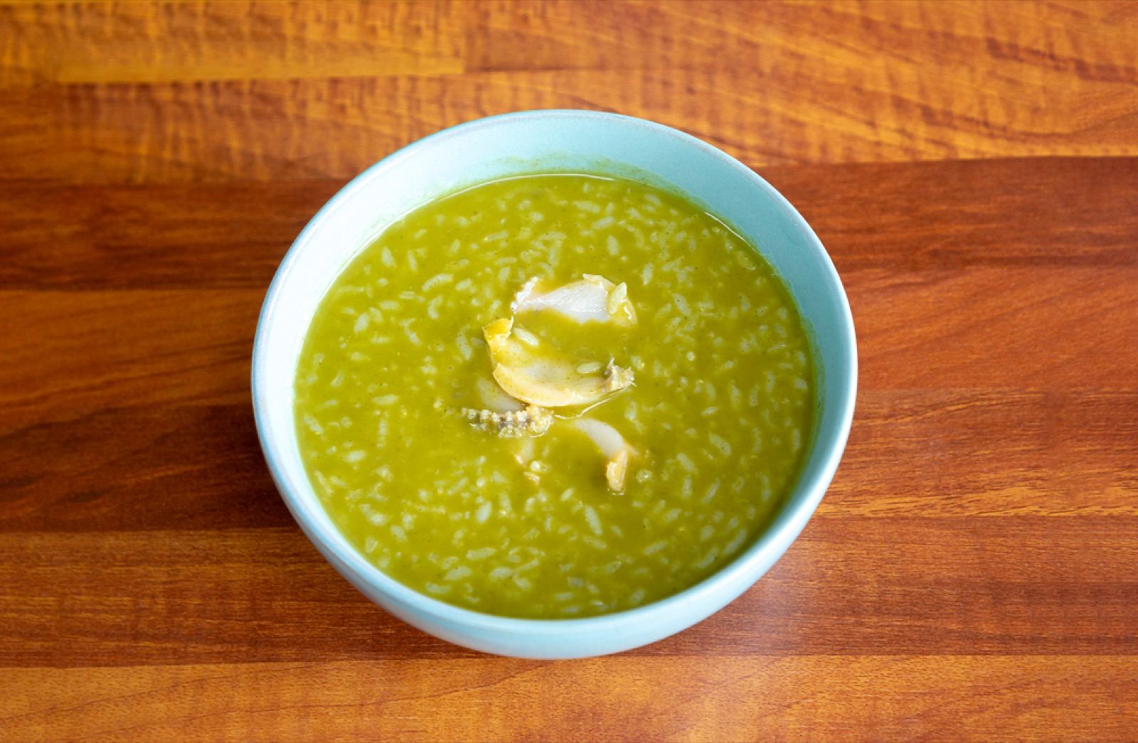 A bowl of jeonbok-juk, green-tinged Jeju abalone rice porridge, with slices of abalone on top